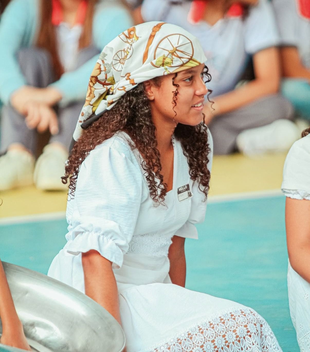 Aluna com lenço na cabeça sorrindo durante apresentação